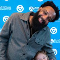 Gentleman posing for photo with small kid in front of back drop